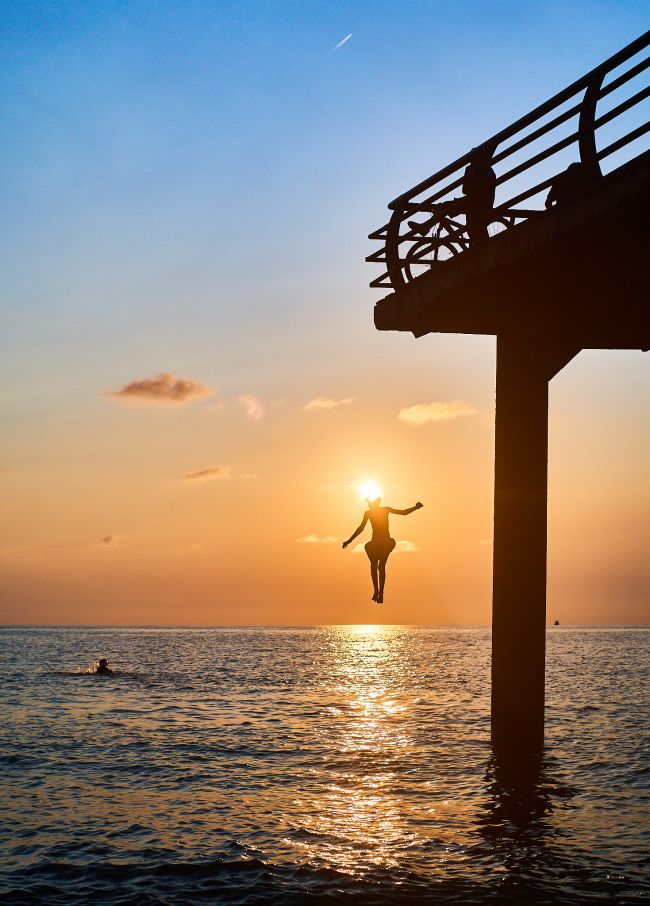 boy jumping from the pier in the sun