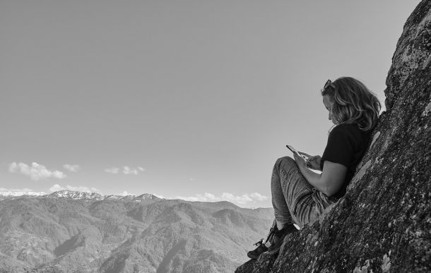 girl sitting on the summit with mountains in the background